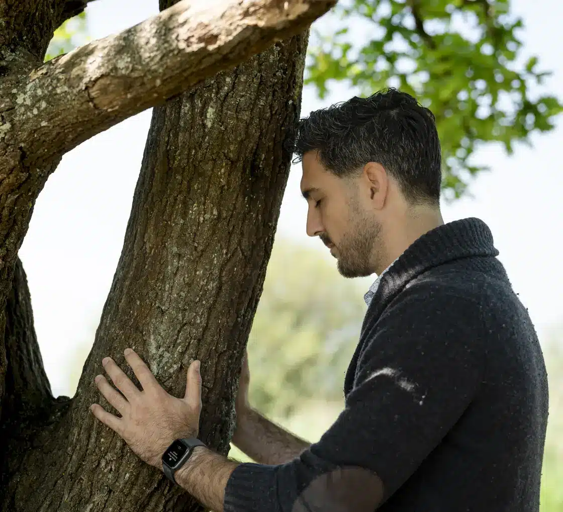 Romain Sol, la main posée sur le tronc d'un arbre